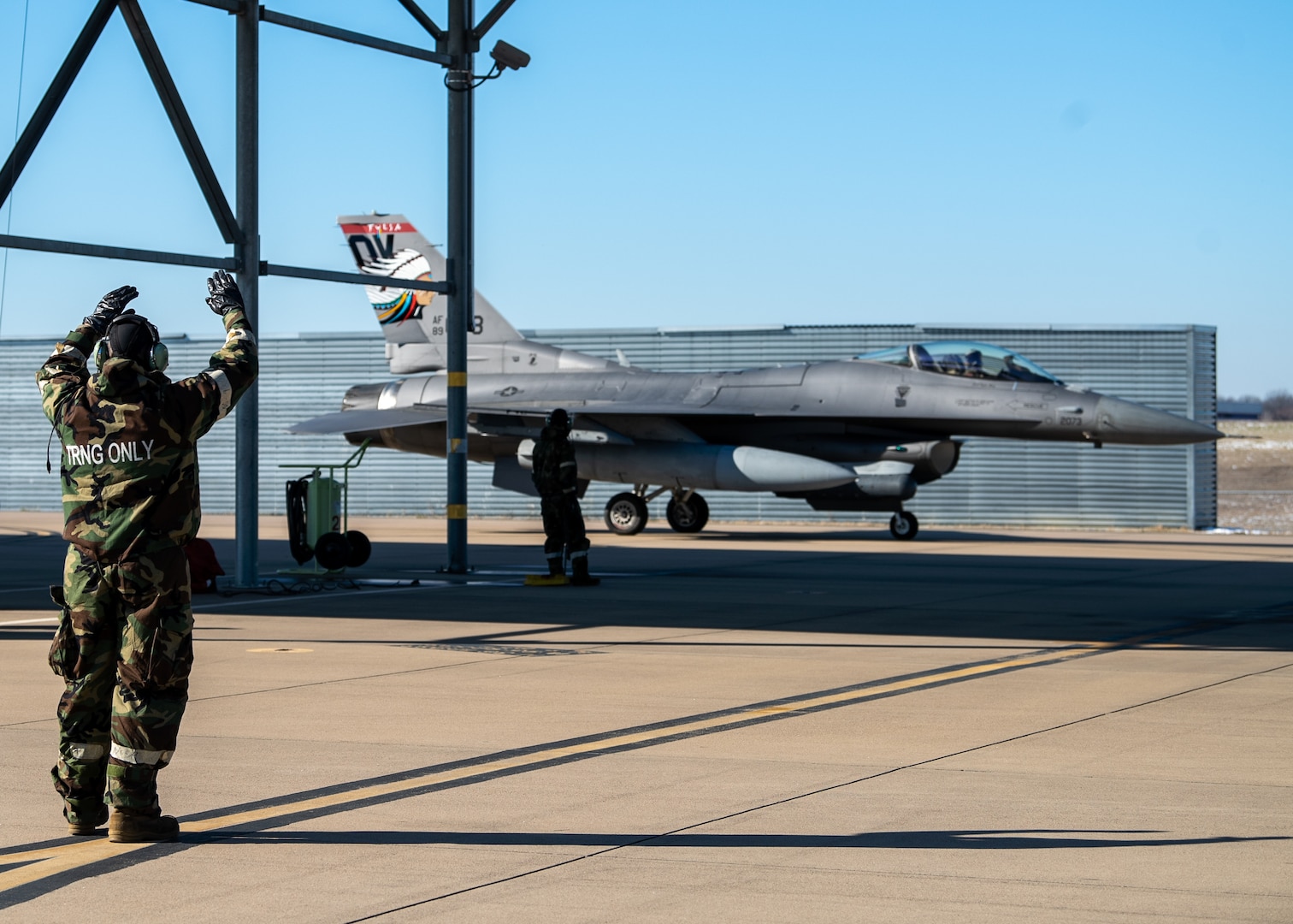 A 138th Aircraft Maintenance Squadron crew chief directs a F-16 Viper to a parking spot during a base wide exercise at Tulsa Air National Guard Base, Okla., Jan. 12, 2025. After a jet has landed, the chief and their crew take over after the pilot to begin inspecting, refueling and repairing the jet to ensure it remains mission ready at all times and ensures the Wing is capable and ready to succeed. (Oklahoma Air National Guard photo by Senior Airman Addison Barnes)