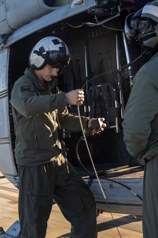 U.S. Marine Corps Cpl. Joshua Stevens, a UH-1Y Venom helicopter crew chief with Marine Light Attack Helicopter Squadron (HMLA) 367, Marine Aircraft Group 39, 3rd Marine Aircraft Wing, inspects a wire connected to a Bambi Bucket on a UH-1Y Venom at Marine Corps Air Station Camp Pendleton, California, Jan. 10, 2025.