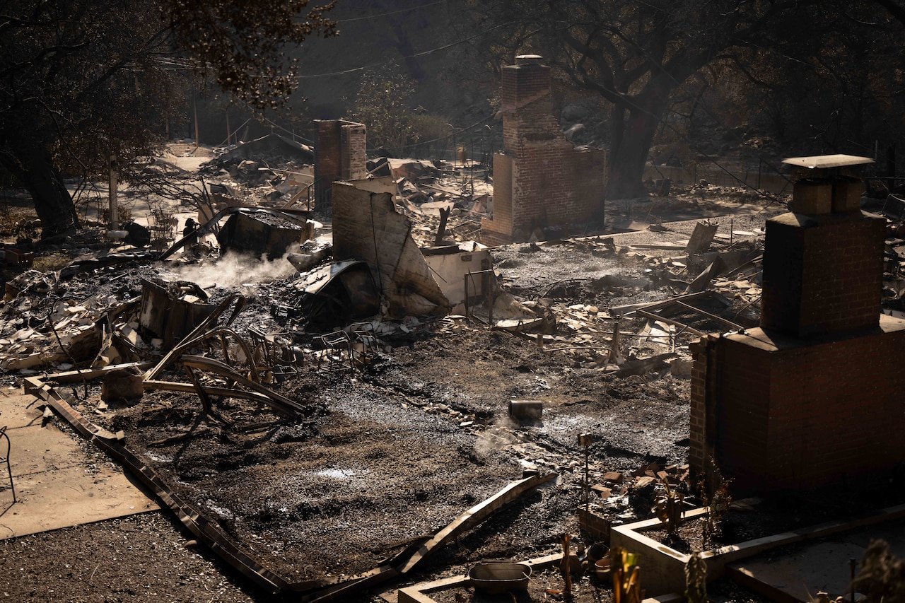 A building lies in ash and ruins after a wildfire passed through during the day.