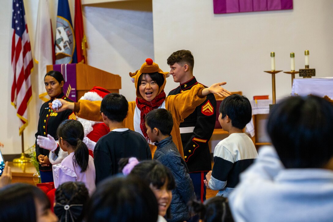 Shiori Minato, an admin specialist with the Marine Corps Air Station Iwakuni chapel, announces the snowball fight winner during a holiday party held at the Marine Memorial Chapel, MCAS Iwakuni, Japan, Dec. 14, 2024. The chaplain services of Headquarters and Headquarters Squadron, MCAS Iwakuni host this annual holiday party to foster a healthy and positive relationship between base personnel and the local community, by bringing gifts, participating in games, and sharing in American holiday traditions. (U.S. Marine Corps photo by Lance Cpl. Micah Taylor)