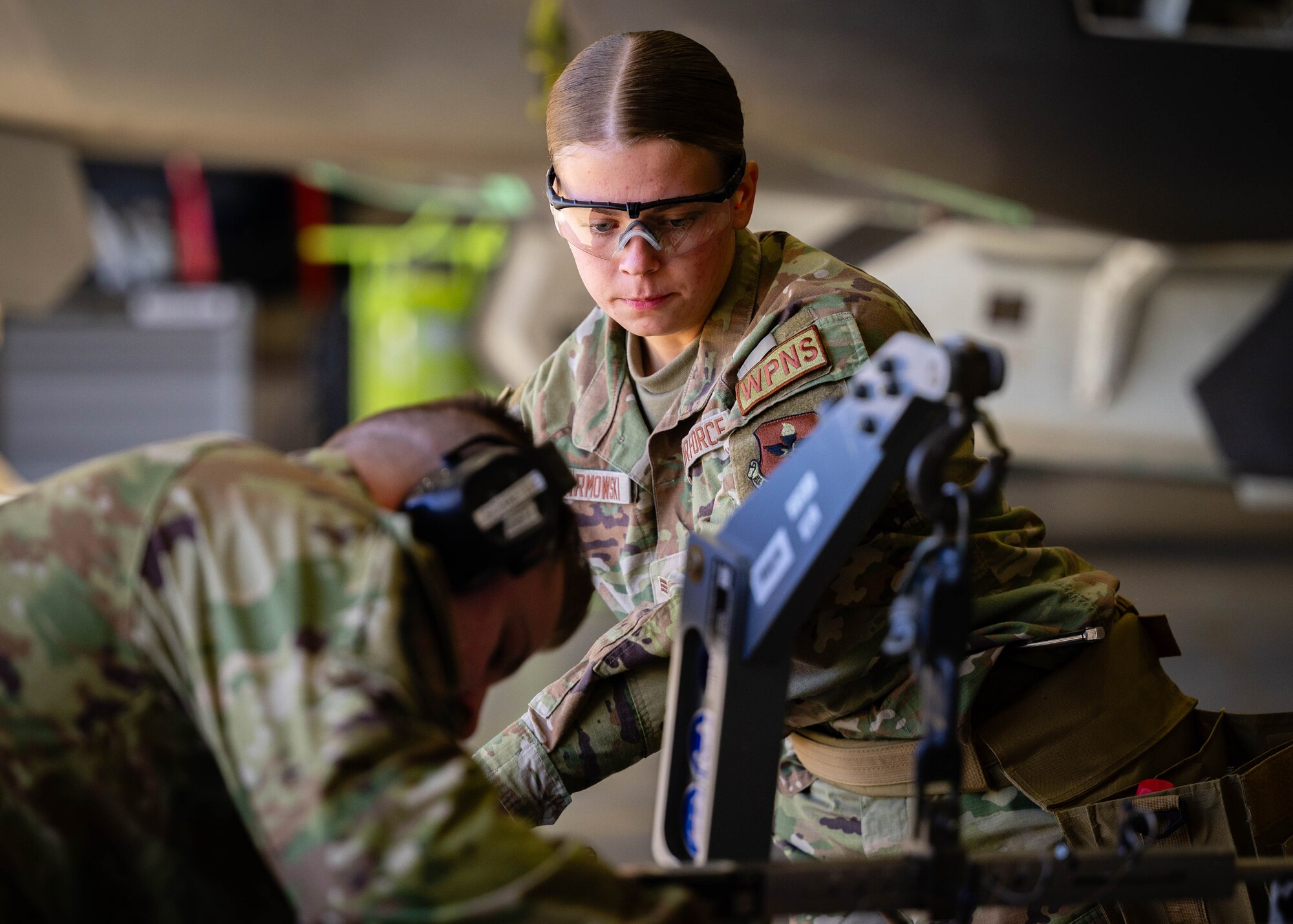 U.S. Air Force Senior Airman Preston Warmowski (right), 308th Aircraft Maintenance Unit maintainer, and Staff Sgt. Luke Schaetzle (left), 308th AMU weapons team chief, secure a piece of equipment onto a U.S. Air Force F-35 Lightning II.