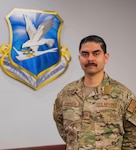 Looking at the camera, Bautista poses for a photo with the AFSFC shield behind him.
