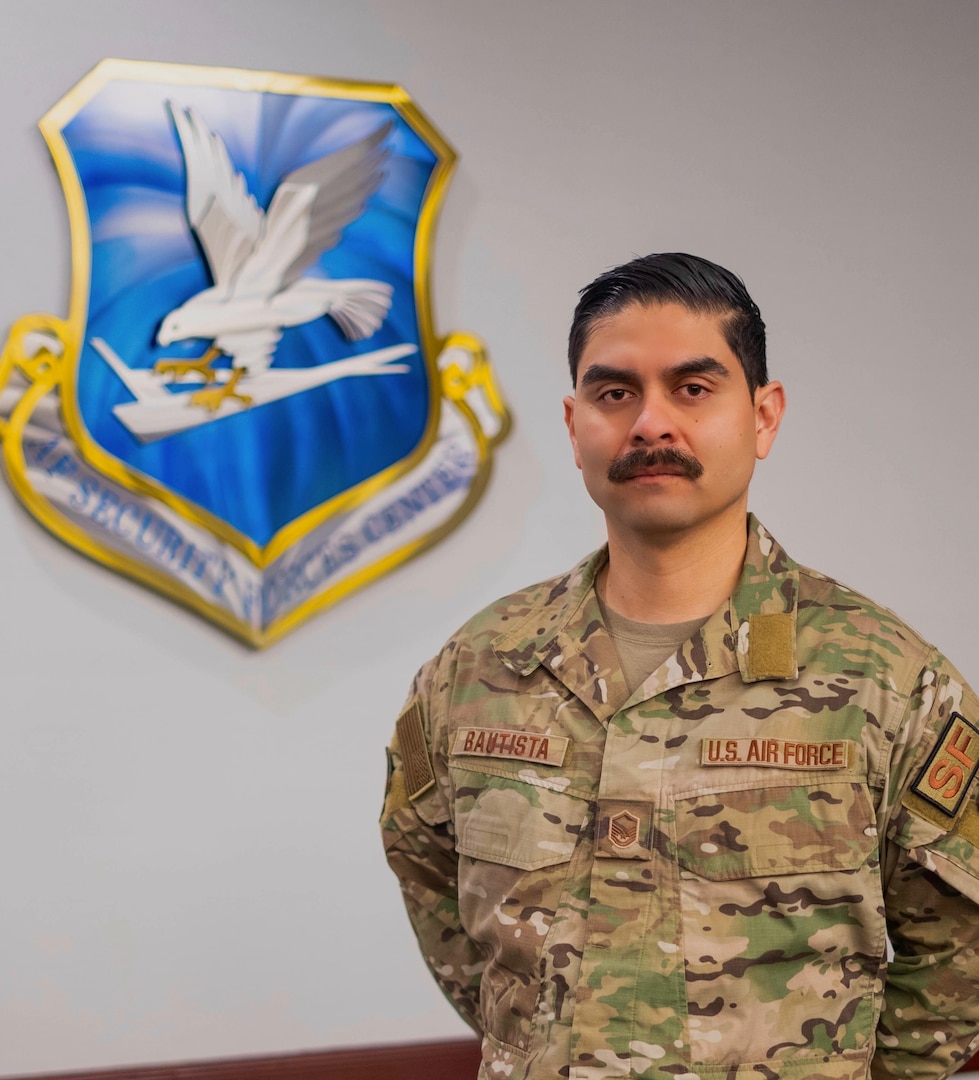 Looking at the camera, Bautista poses for a photo with the AFSFC shield behind him.
