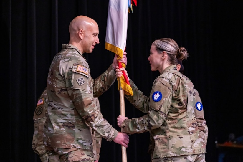 Two soldiers hold a flag pole.