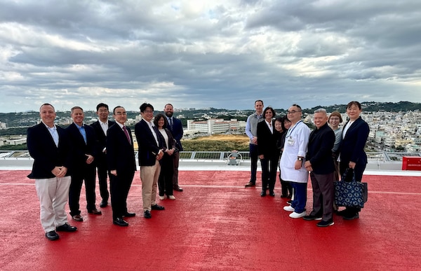 Staff from the JGSDF at the Naha hospital, staff from USNHO, and staff from the University of the Ryukyus, touring the new hospital with USNHO in the background.