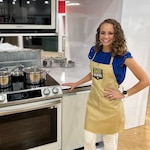 WVNG Dietitian Shari Wright Pettit stands an oven, smiling at the camera and wearing a WV Army National Guard apron.