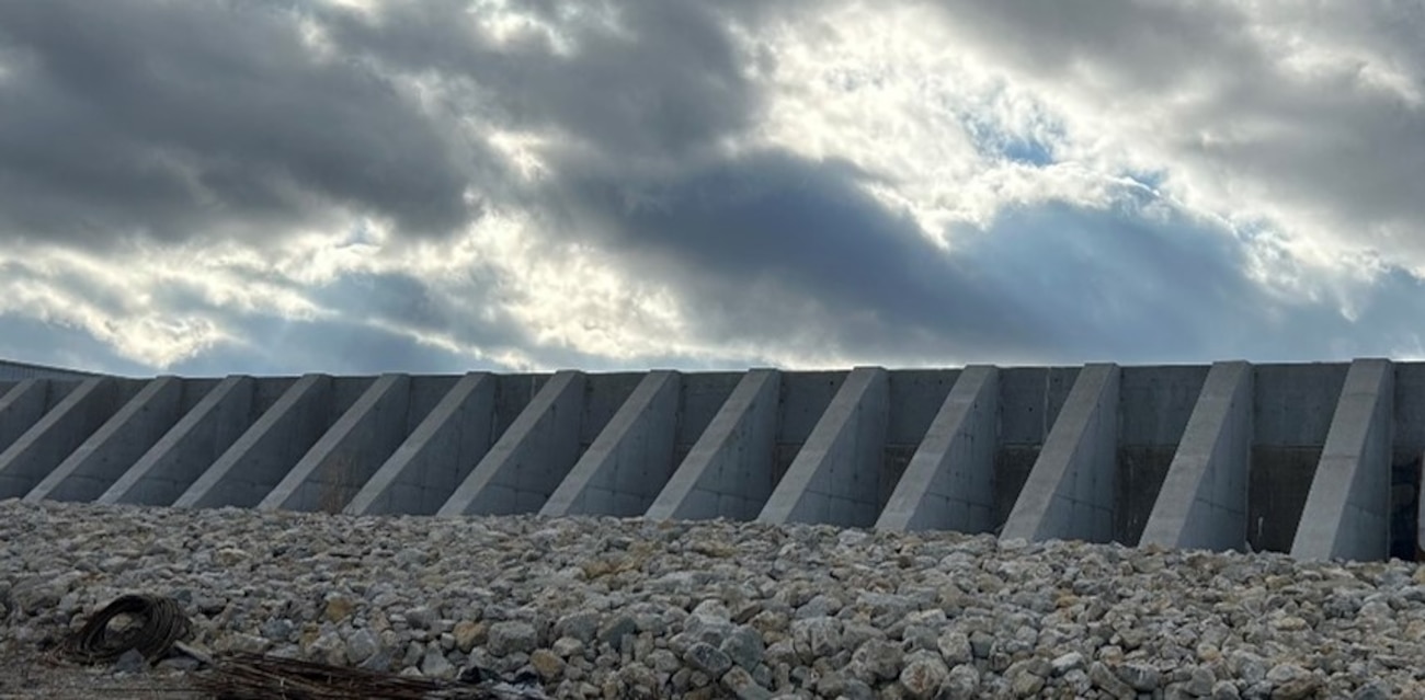 Buttressed concrete floodwall with riprap in foreground