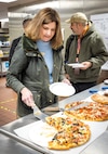 Julia McLaughlin, director, Morale Welfare and Recreation, Naval Base Kitsap-Bremerton, dishes up a slice of freshly baked pizza from the Picnic Pizza Station, a new automated pizza oven, Dec. 9, 2024, inside the Building 435 cafeteria at Puget Sound Naval Shipyard & Intermediate Maintenance Facility in Bremerton, Washington. (U.S. Navy photo by Wendy Hallmark)