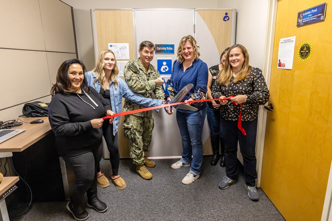 Capt. JD Crinklaw, left, commander, Puget Sound Naval Shipyard & Intermediate & Intermediate Maintenance Facility, participates in an official ribbon-cutting ceremony inside Building 844, Nov. 22, 2024, for one of three new expressing station pods to support nursing mothers working at PSNS & IMF in Bremerton, Washington. (U.S. Navy photo by Jeb Fach)