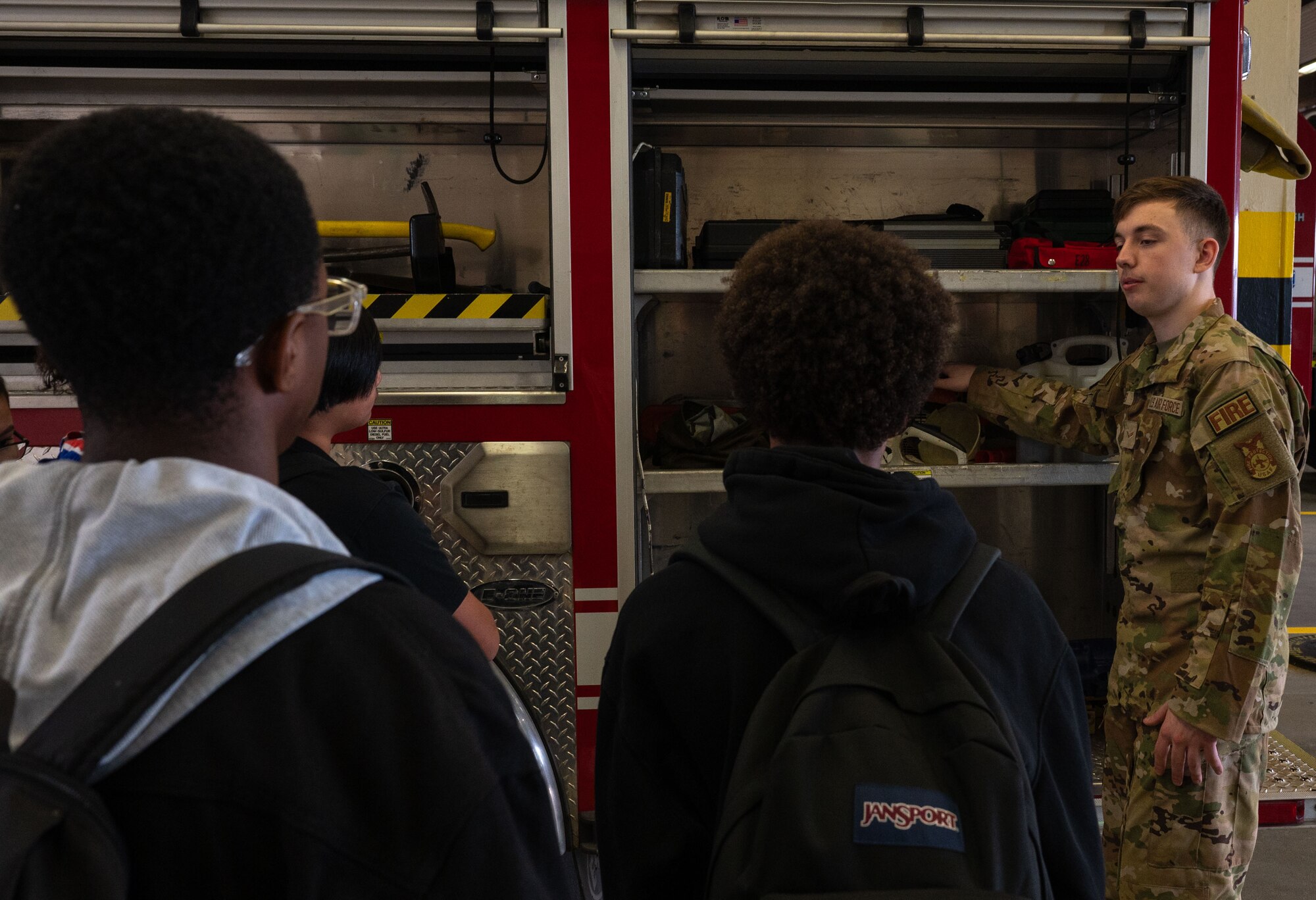 A man shows fire fighter equipment to students