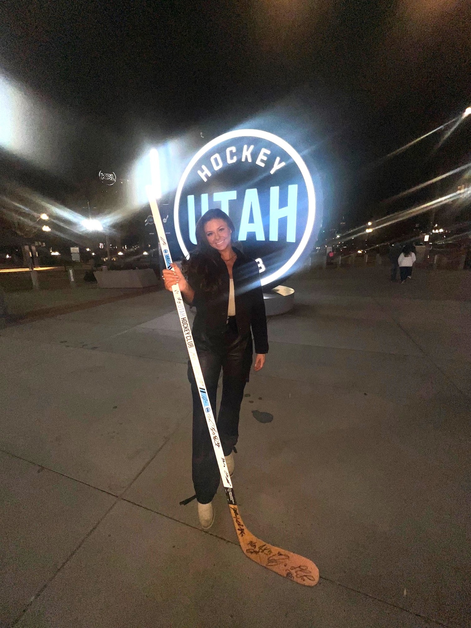 A woman displays an autographed hockey stick outside in front of a sports arena
