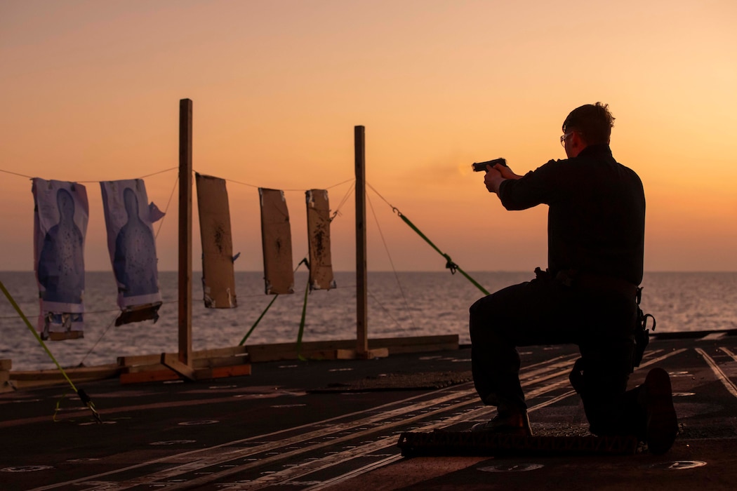 A fire controlman shoots an M9 service pistol aboard USS Gettysburg (CG 64).