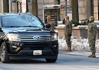 Marines salute as a vehicle passes by