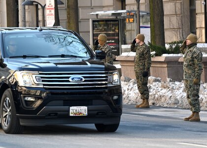 Marines salute as a vehicle passes by