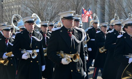 Members of U.S. Marine Band march holding instruments under their arms