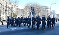Airmen march in a parade holding rifles