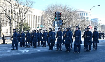 Airmen march in a parade holding rifles