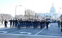 Soldiers march in a parade carrying instruments