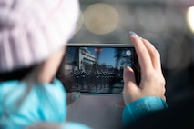 Civilian using their phone to take photos of the parade rehearsal