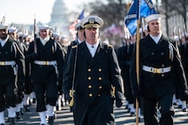 Sailors marching in formation with officer in the front