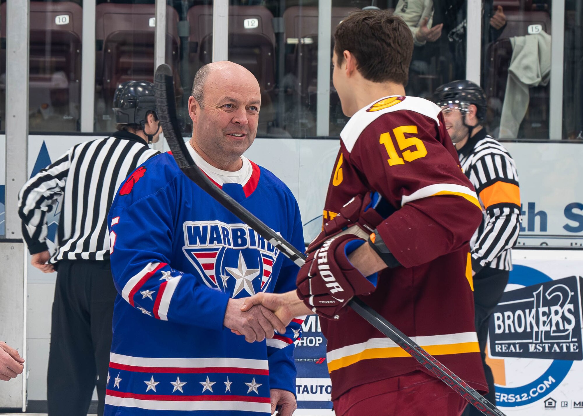 U.S. Air Force Col. Benjamin Jensen (left), 5th Bomb Wing deputy commander, and Jacob Schuldt, Iowa State University Cyclones defenseman, shake hands during the Minot State University military appreciation hockey game at Maysa Arena, Minot, North Dakota, Jan. 11, 2025. Jensen participated in a ceremonial puck drop to begin the game. (U.S. Air Force photo by Senior Airman Kyle Wilson)