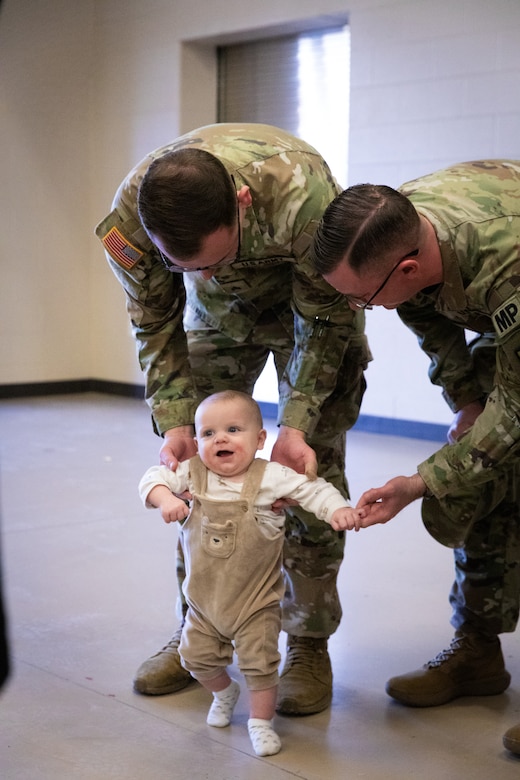 U.S. Army Sgt. Samuel Sutherland helps his son walk while Sgt. Aaron Williams watches at the 617th Military Police Company deployment ceremony at the Armed Forces Reserve Center in Richmond, Kentucky on Jan. 4, 2025.