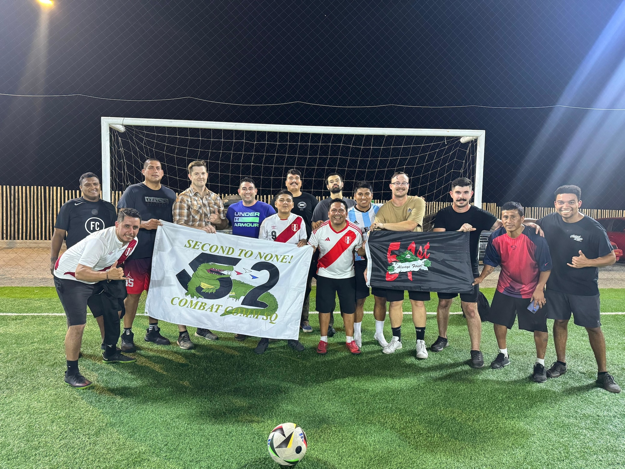 Airmen and Peruvians hold flags together on a soccer field