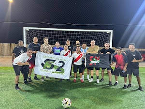 Airmen and Peruvians hold flags together on a soccer field