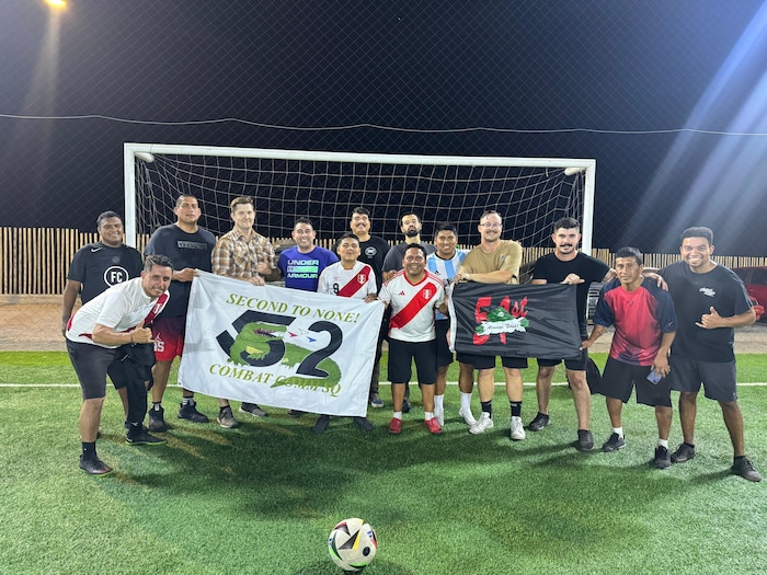 Airmen and Peruvians hold flags together on a soccer field