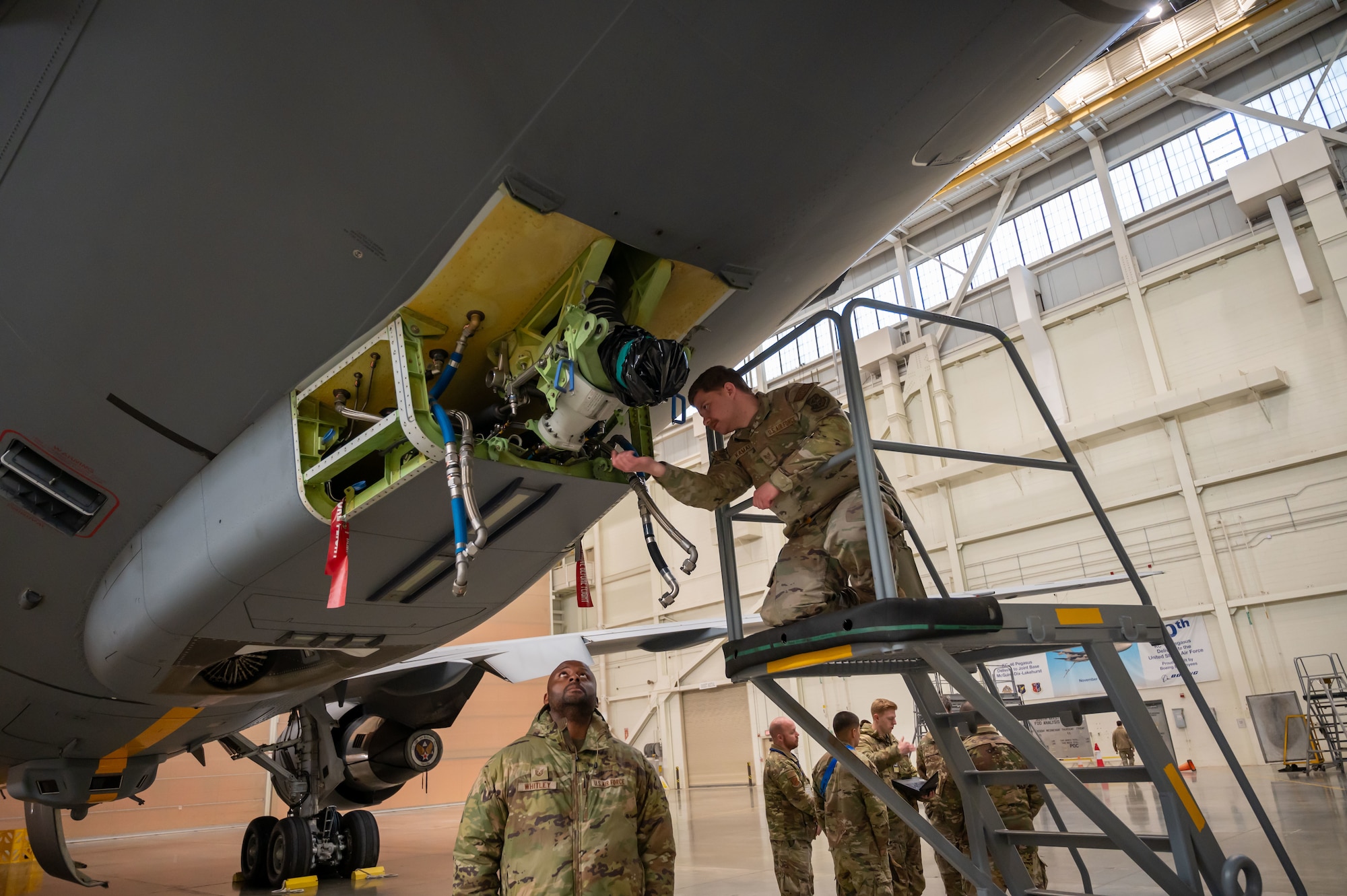 U.S. Air Force Staff Sgt. Jeremy Kamai, 605th Aircraft Maintenance Squadron hydraulics craftsman, and Tech. Sgt. Brandon Whitley, 605th AMXS flying crew chief, inspect the KC-46A Pegasus aircraft boom gimbal yoke nut at Joint Base McGuire-Dix-Lakehurst, N.J., Jan. 14, 2025. The inspection of the component ensures the boom gimbal stays attached to the aircraft properly and allows the boom to roll and pivot as needed in flight safely. (U.S. Air Force photo by Susan Moriarty)