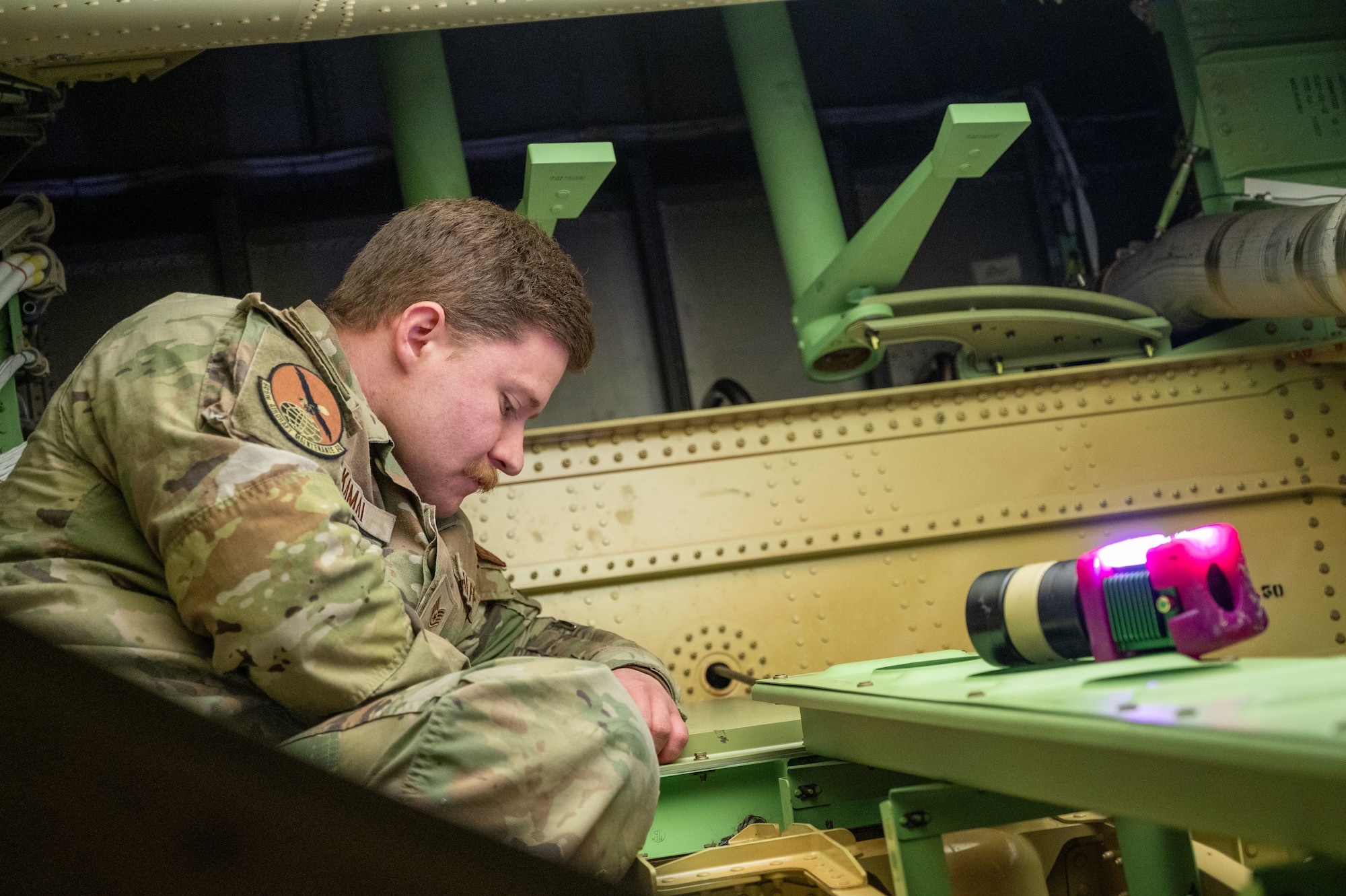 U.S. Air Force Staff Sgt. Jeremy Kamai, 605th Aircraft Maintenance Squadron hydraulics craftsman, removes the boom latch compartment access cover inside the KC-46A Pegasus aircraft to complete a time compliance technical order at Joint Base McGuire-Dix-Lakehurst, N.J., Jan. 14, 2025. The TCTO required removing, disassembling, cleaning and testing the force required to actuate the hook on the latch assembly for the boom to ensure the latch will not seize or bind during the stowing operations after the flight crew is done using the boom in flight. (U.S. Air Force photo by Susan Moriarty)