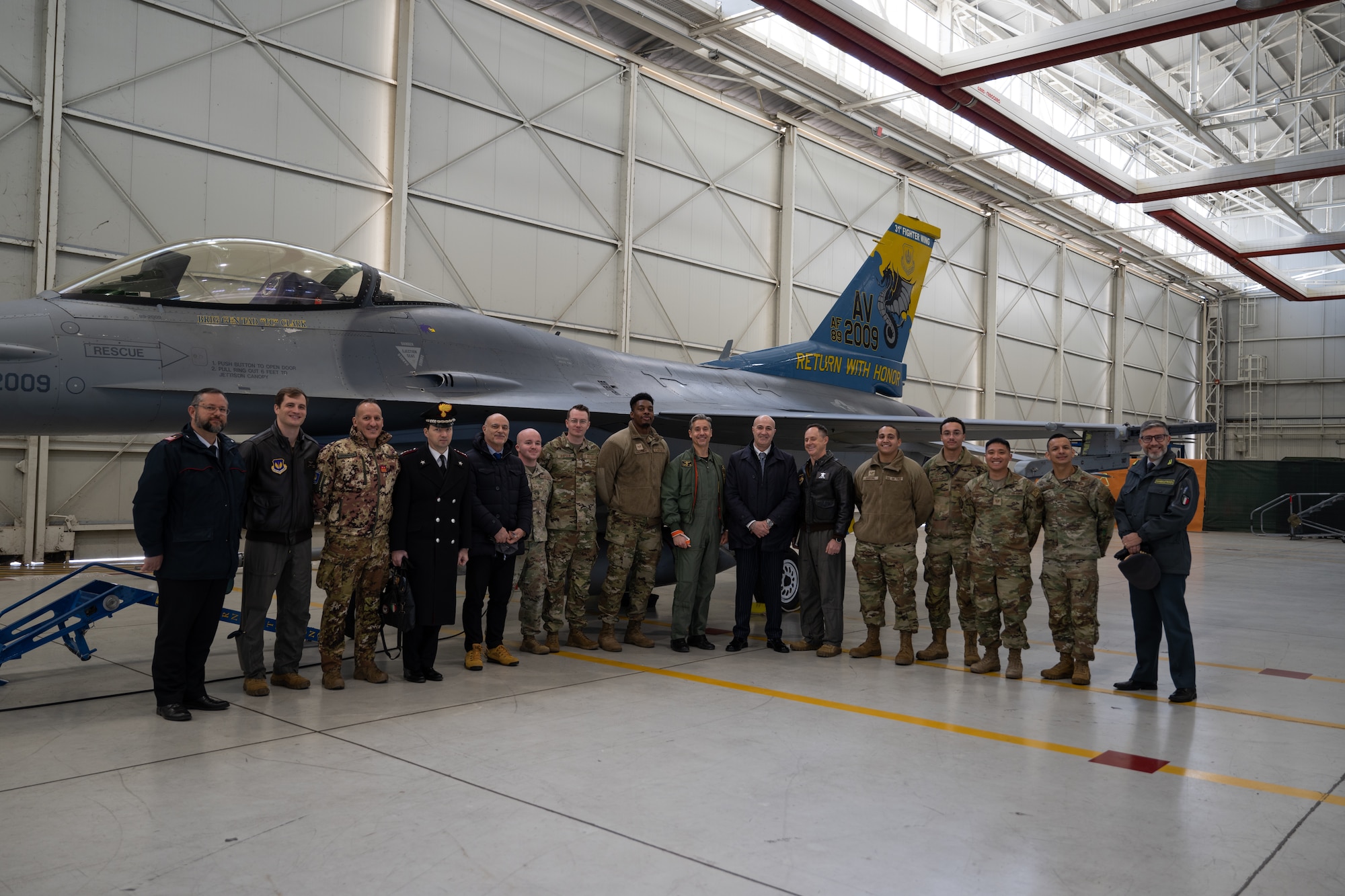 Leadership from Aviano Air Base and the local Italian community pose for a photo with an F-16 Fighting Falcon at Aviano Air Base, Italy, Jan. 14, 2025.