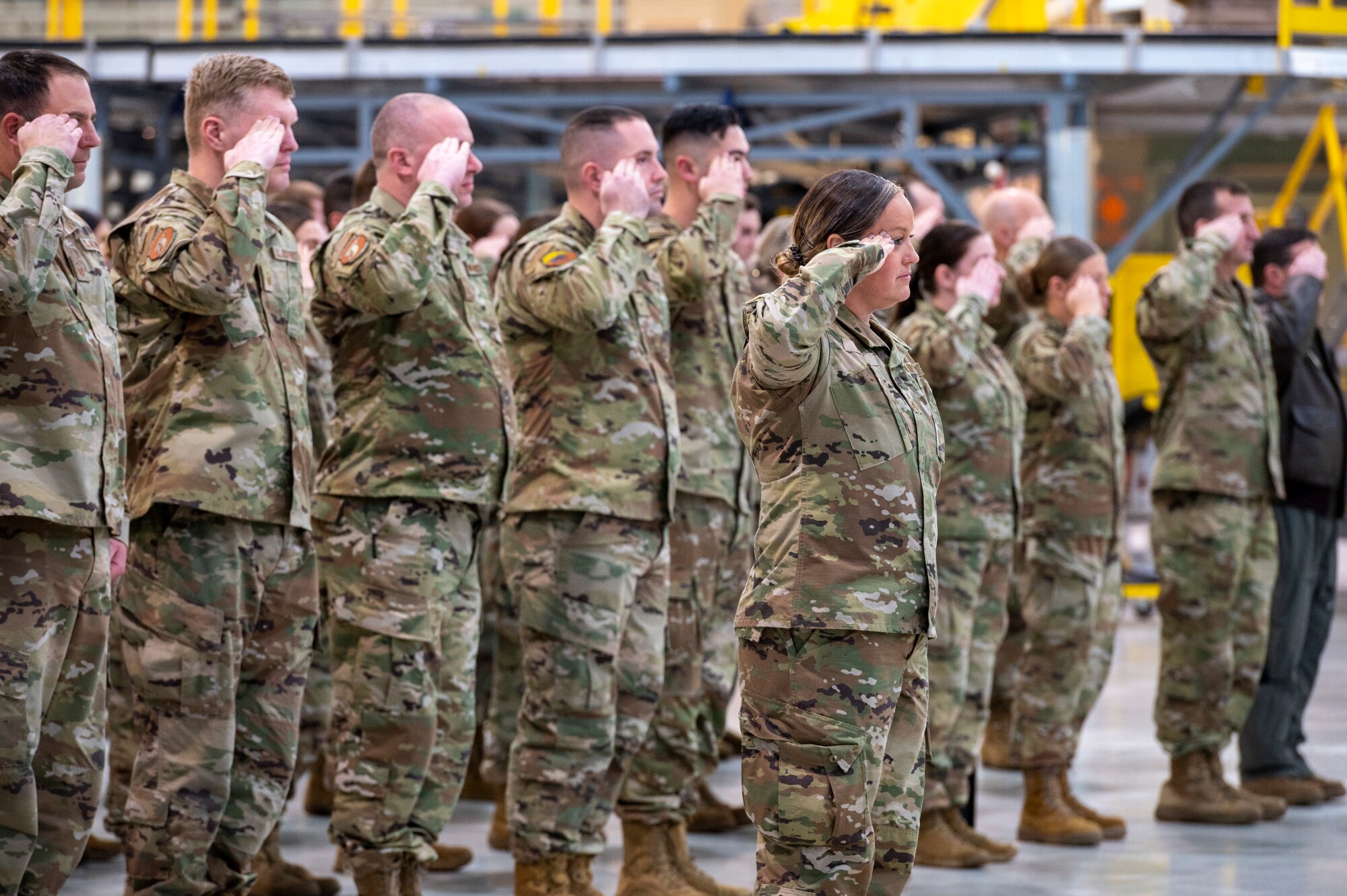 men and women stand in formation and render a salute