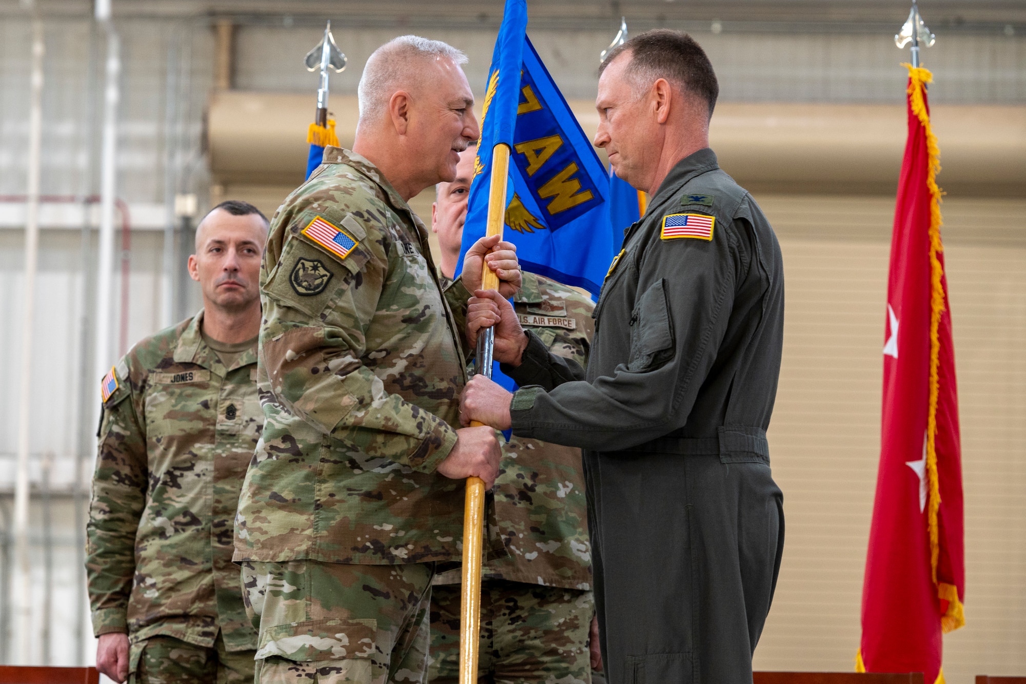 two men in uniform grip a guidon on a stage