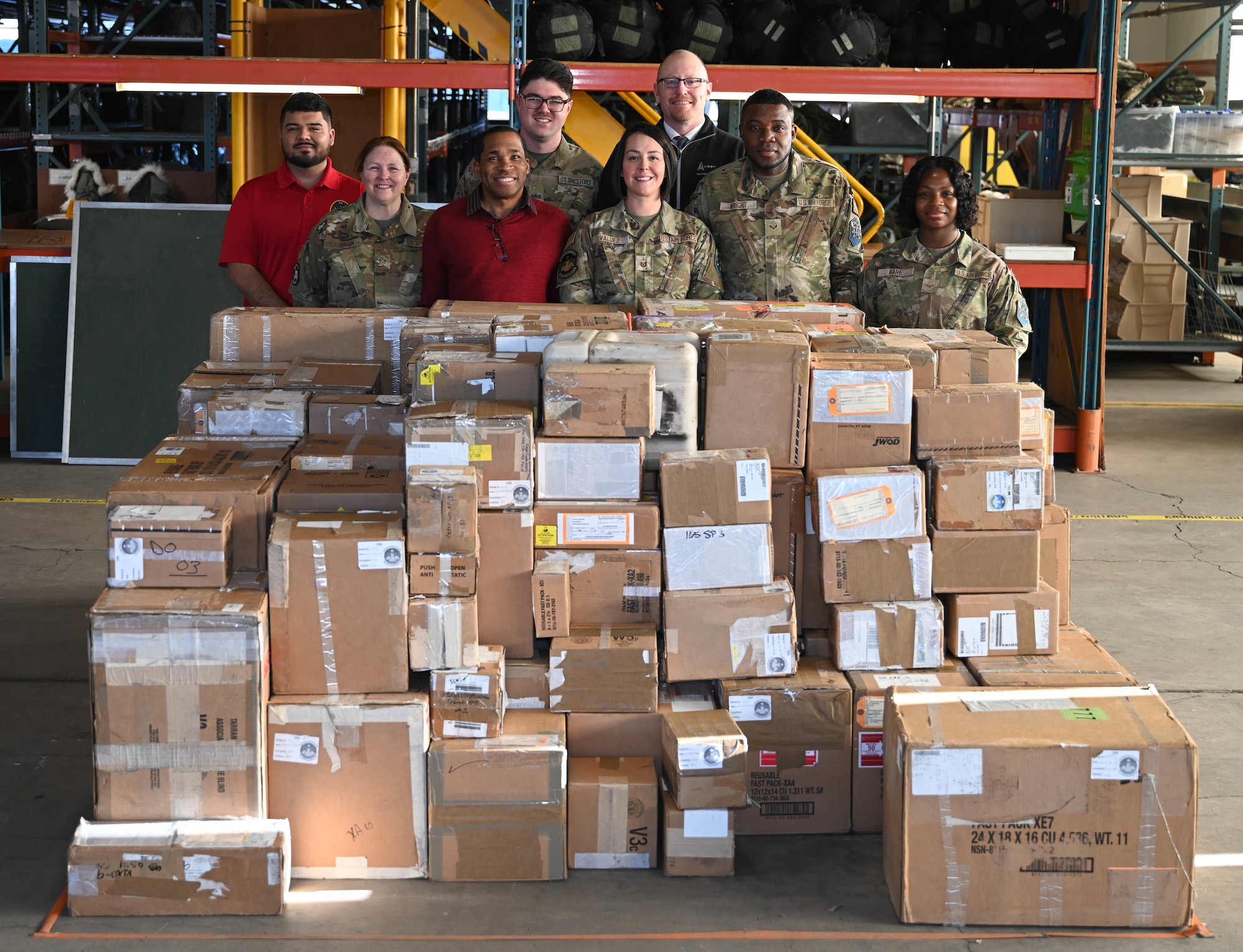 Participants stand behind stacked boxed during the space logistics challenge at Peterson Space Force Base, Colorado, Jan. 15, 2025. The challenge was the first step to optimize artificial intelligence in loading a miliary container with cargo, setting up a baseline with hopes of improving the loading process for the future. (U.S. Space Force photo by Staff Sgt. Jaime Sanchez)