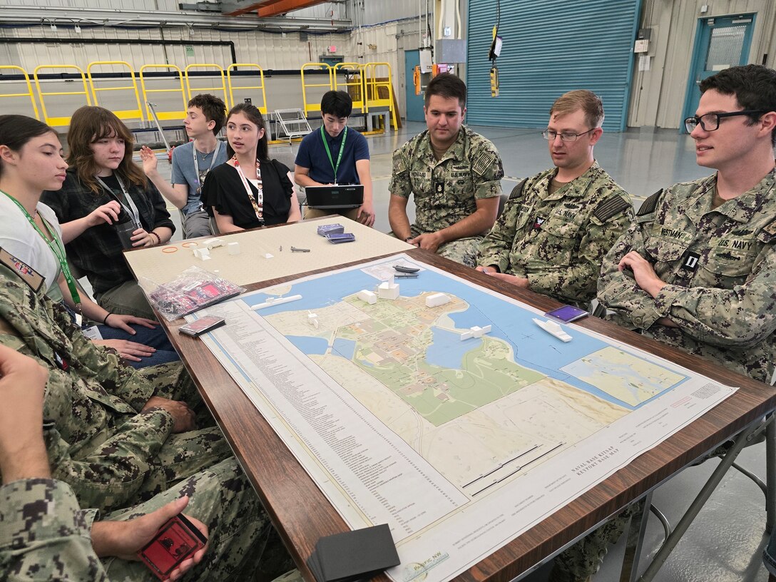 From left to right: High school students Hana Knight, Priscila MacDonald, Ethan Kohlmeyer-Hyman, Maya Knight and Kai Livingston, along with Unmanned Undersea Vehicle Group ONE Sailors Petty Officer Daniel Leno, Petty Officer Christian Lamb, Chief Petty Officer Matthew Howard, Petty Officer Zachary Amsden and Lt. Mark Westman, pictured Aug. 2 during an internship at Naval Undersea Warfare Center Division, Keyport. The students were part of a team of 10 interns who surpassed expectations in their development of an innovative tabletop cybersecurity game called SEACAT. (U.S. Navy photo by Jacob Yakawich/Released)