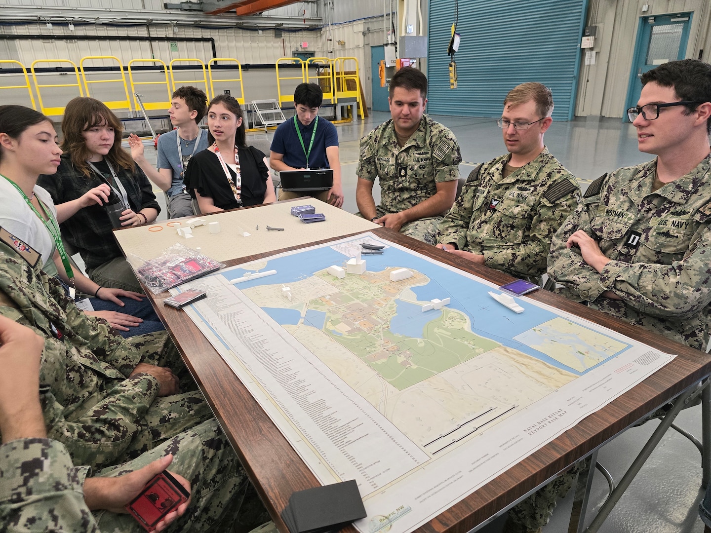 From left to right: High school students Hana Knight, Priscila MacDonald, Ethan Kohlmeyer-Hyman, Maya Knight and Kai Livingston, along with Unmanned Undersea Vehicle Group ONE Sailors Petty Officer Daniel Leno, Petty Officer Christian Lamb, Chief Petty Officer Matthew Howard, Petty Officer Zachary Amsden and Lt. Mark Westman, pictured Aug. 2 during an internship at Naval Undersea Warfare Center Division, Keyport. The students were part of a team of 10 interns who surpassed expectations in their development of an innovative tabletop cybersecurity game called SEACAT. (U.S. Navy photo by Jacob Yakawich/Released)