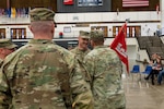 U.S. Army Capt. Ricky Kuhn, 817th Engineer Company, Sapper, outgoing commander, left, watches as Lt. Col. Steven Bohl, 164th Engineer Battalion commander, passes the 817th Engineer Company, Sapper, guidon to his older brother, Capt. Toby Kuhn, signifying the relinquishing of command, during the change of command ceremony in Jamestown, North Dakota, Jan. 12, 2025. The brothers enlisted into the U.S. Army at different times, but both commissioned in 2017.