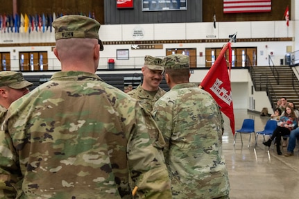 U.S. Army Capt. Ricky Kuhn, 817th Engineer Company, Sapper, outgoing commander, left, watches as Lt. Col. Steven Bohl, 164th Engineer Battalion commander, passes the 817th Engineer Company, Sapper, guidon to his older brother, Capt. Toby Kuhn, signifying the relinquishing of command, during the change of command ceremony in Jamestown, North Dakota, Jan. 12, 2025. The brothers enlisted into the U.S. Army at different times, but both commissioned in 2017.