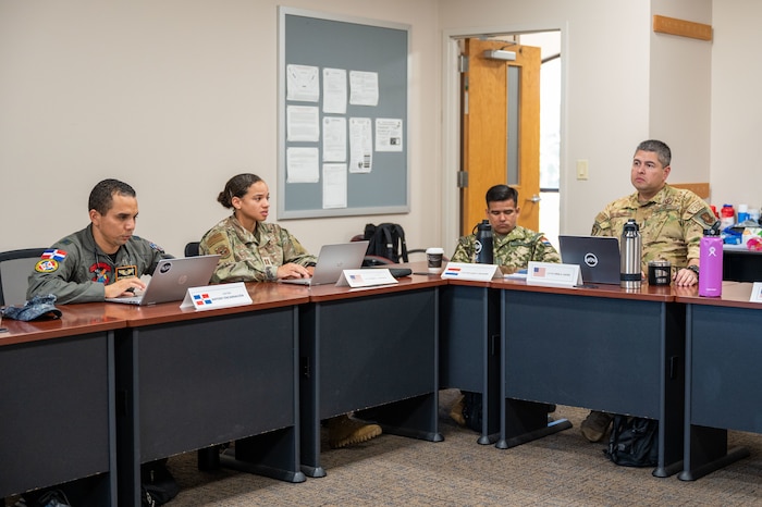 Image of Airmen sitting at a desk.