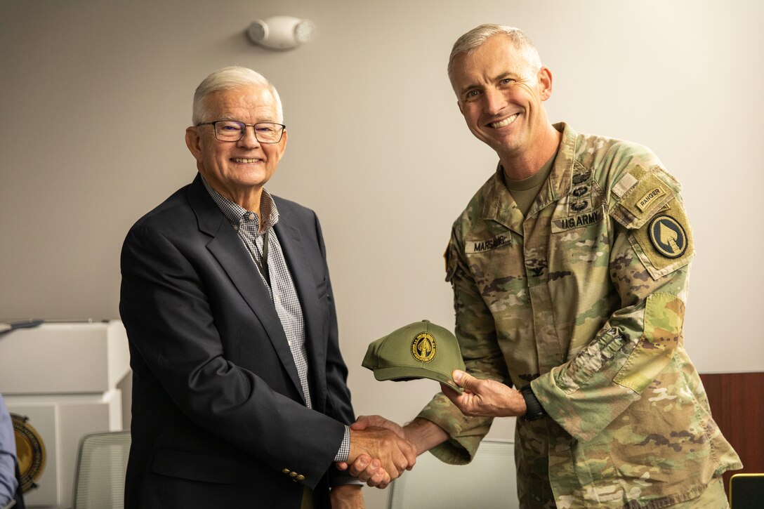 Retired U.S. Army Maj. Gen. Stephen Collins, left, is presented with a special operations forces challenge coin and hat by U.S. Army Col. Jess Marasalis, the program executive officer for Special Operations Forces, at his retirement ceremony at Bluegrass Station in Lexington, Kentucky on Dec. 10, 2025.