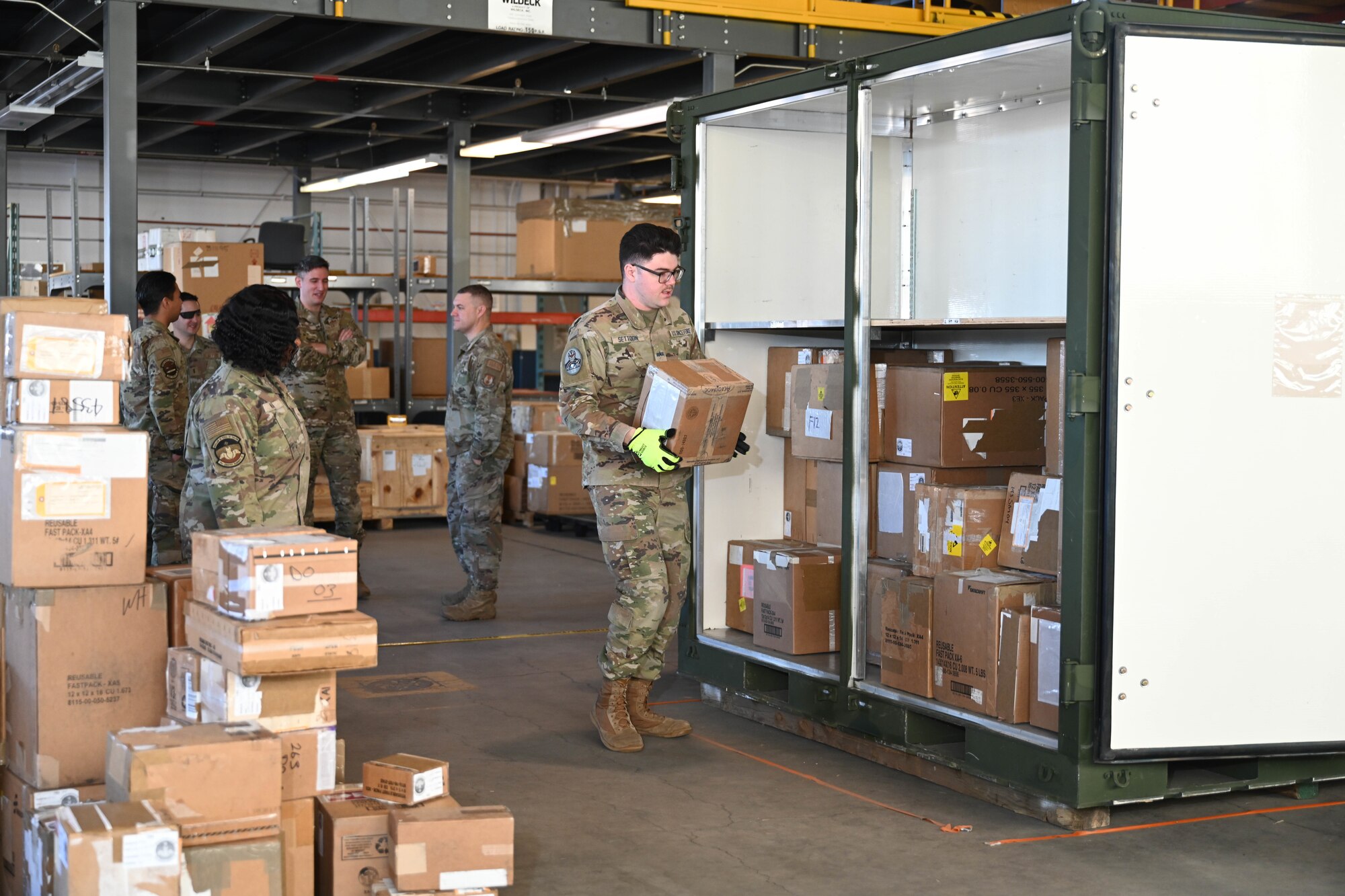 U.S. Space Force Spc. 4 Blake Settoon, 62nd Cyberspace Squadron defensive cyber operator, carries a box to load onto a military container during the space logistics challenge at Peterson Space Force Base, Colorado, Jan. 25, 2025. Settoon was part of the third round of tests for the challenge and his results were used to create a baseline to compare the optimized loading instructions given by artificial intelligence. (U.S. Space Force photo by Staff Sgt. Jaime Sanchez)