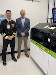 San Antonio, Texas (Dec. 11, 2024) Cmdr. Marshall Hoﬀman, Navy Bloodborne Infection Management Center Oﬃcer in Charge, and Center for Disease Detection Laboratory Manager, Joseph Lyons pose in front of a laboratory device used to test blood samples from Department of the Navy servicemembers for HIV. Navy Bloodborne Infection Management Center, a ﬁeld activity of the Navy and Marine Corps Force Health Protection Command, supports medical readiness and blood supply protection for the Navy and Marine Corps through central management of HIV, Hepatitis B, and Hepatitis C. (US Navy photo by Cmdr. Marshall Hoﬀman/Released)