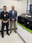 San Antonio, Texas (Dec. 11, 2024) Cmdr. Marshall Hoﬀman, Navy Bloodborne Infection Management Center Oﬃcer in Charge, and Center for Disease Detection Laboratory Manager, Joseph Lyons pose in front of a laboratory device used to test blood samples from Department of the Navy servicemembers for HIV. Navy Bloodborne Infection Management Center, a ﬁeld activity of the Navy and Marine Corps Force Health Protection Command, supports medical readiness and blood supply protection for the Navy and Marine Corps through central management of HIV, Hepatitis B, and Hepatitis C. (US Navy photo by Cmdr. Marshall Hoﬀman/Released)