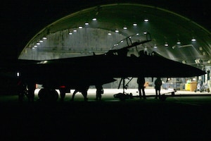 F-15E aircraft parked in front of protective aircraft shelter.