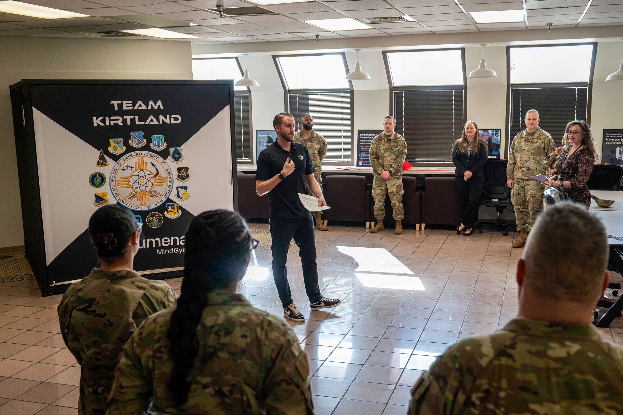 Man in black speaks to a crowd of military members