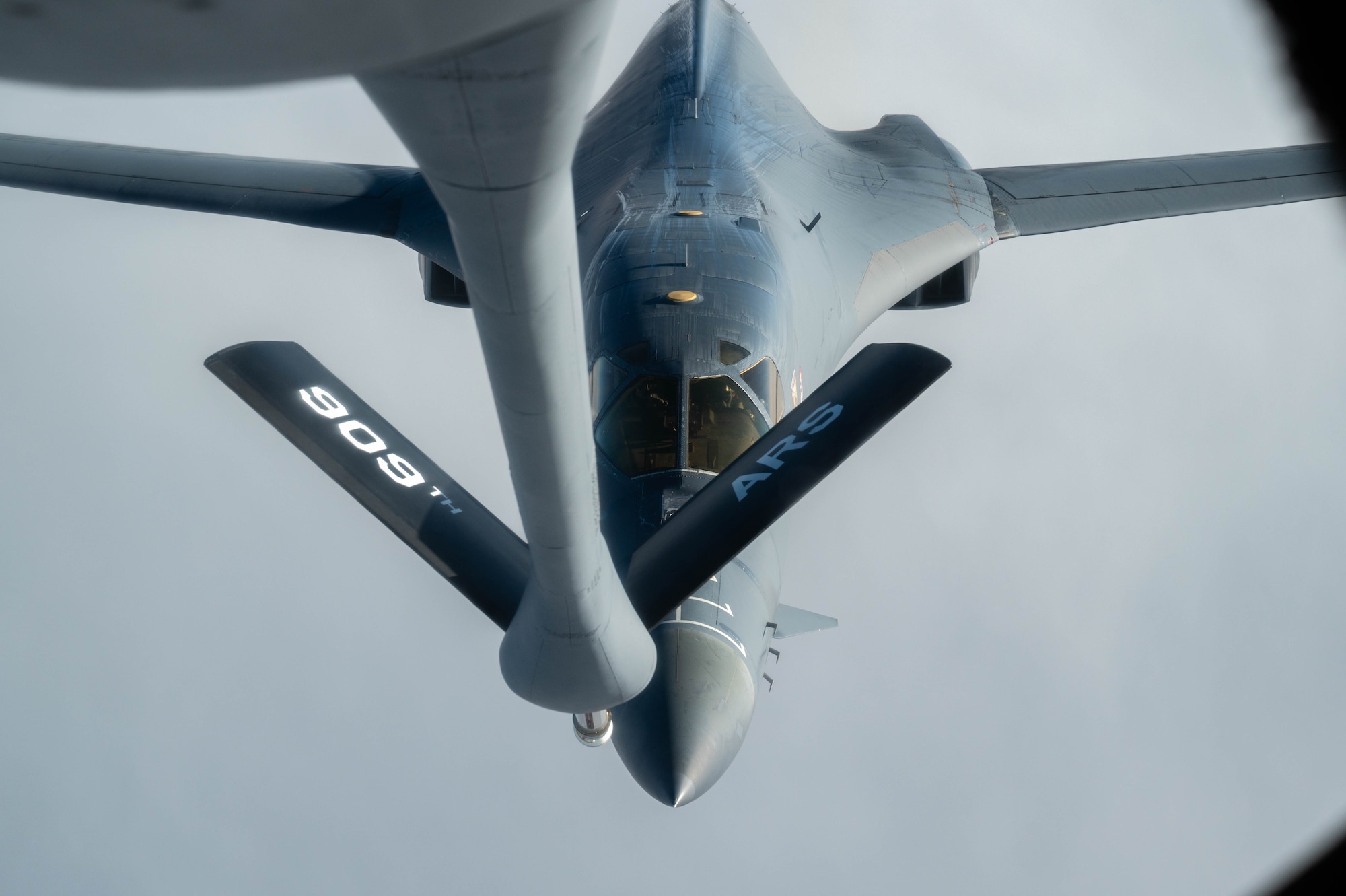 A bomber approaches a boom to conduct aerial refueling.