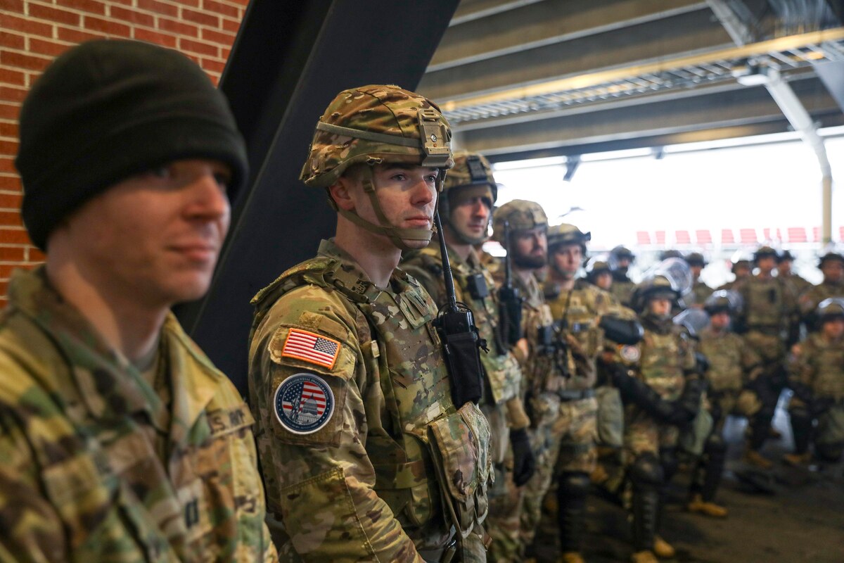 Uniformed service members stand shoulder to shoulder.