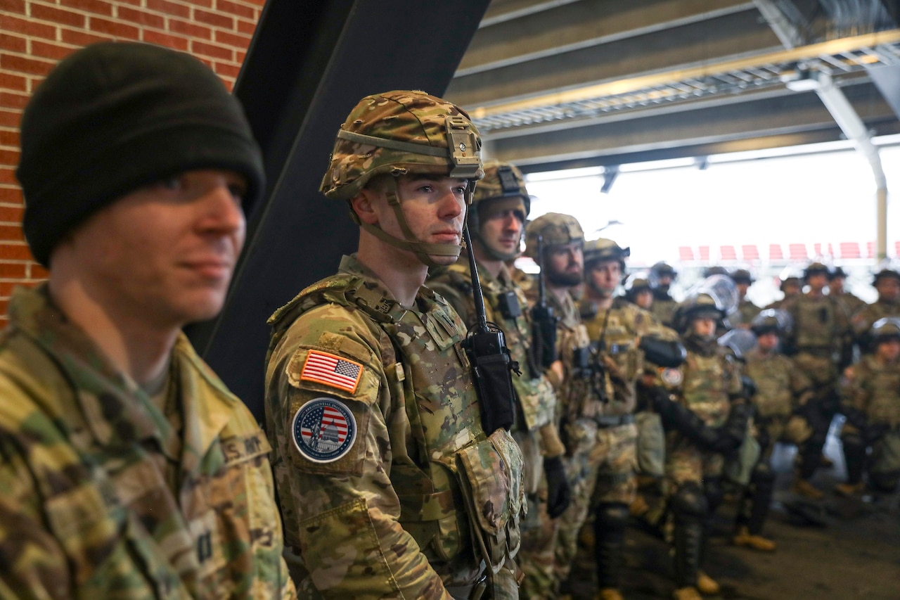 Uniformed service members stand shoulder to shoulder.