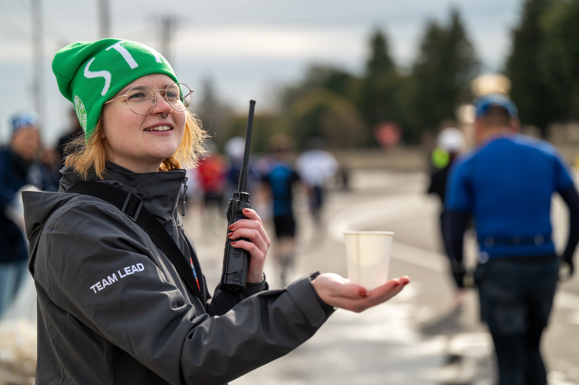 U.S. Air Force Staff Sgt. Alison Riley, 374th Comptroller Squadron financial technician, hands water to half-marathon runners during the 44th Annual Frostbite Road Race at Yokota Air Base, Japan.